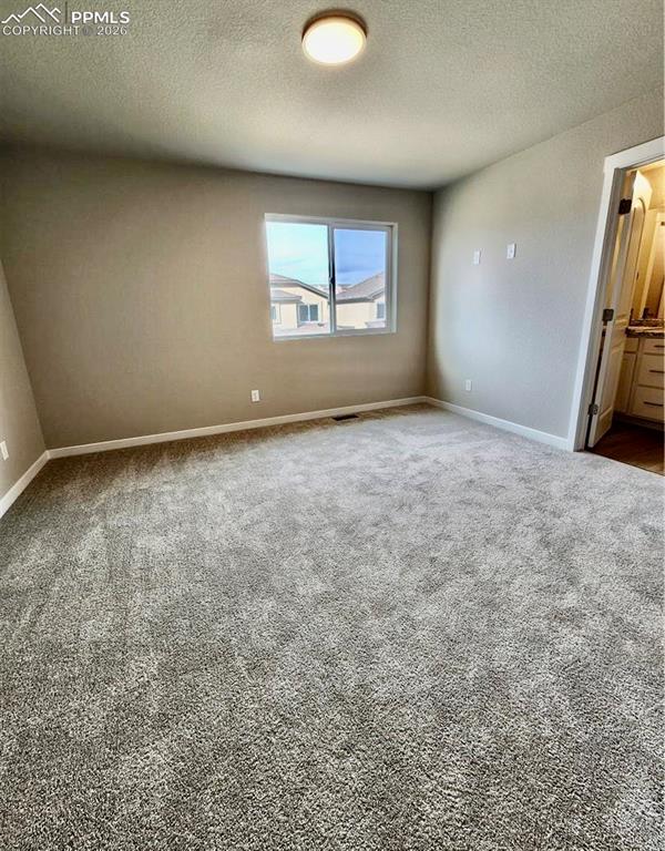Unfurnished room featuring dark carpet and a textured ceiling