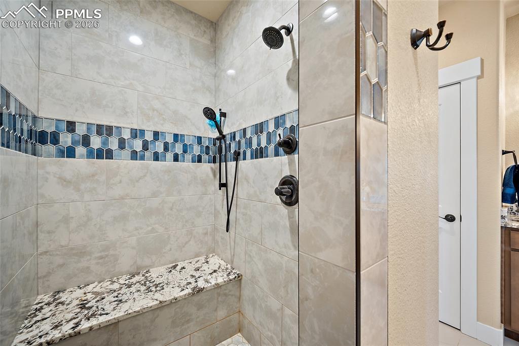 Tile shower with dual shower heads and quartz bench.
