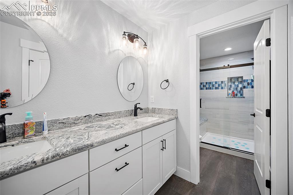 Lower level bathroom with dual vanities, quartz countertops and tile shower.