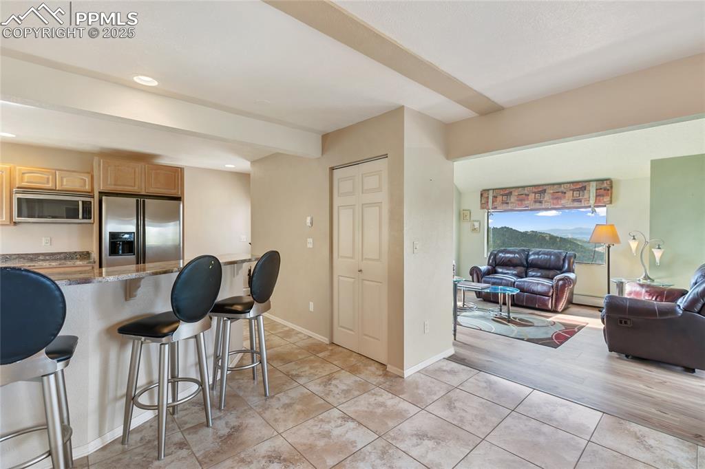 Kitchen with a kitchen bar, dark stone counters, stainless steel appliances, light tile patterned flooring, and recessed lighting