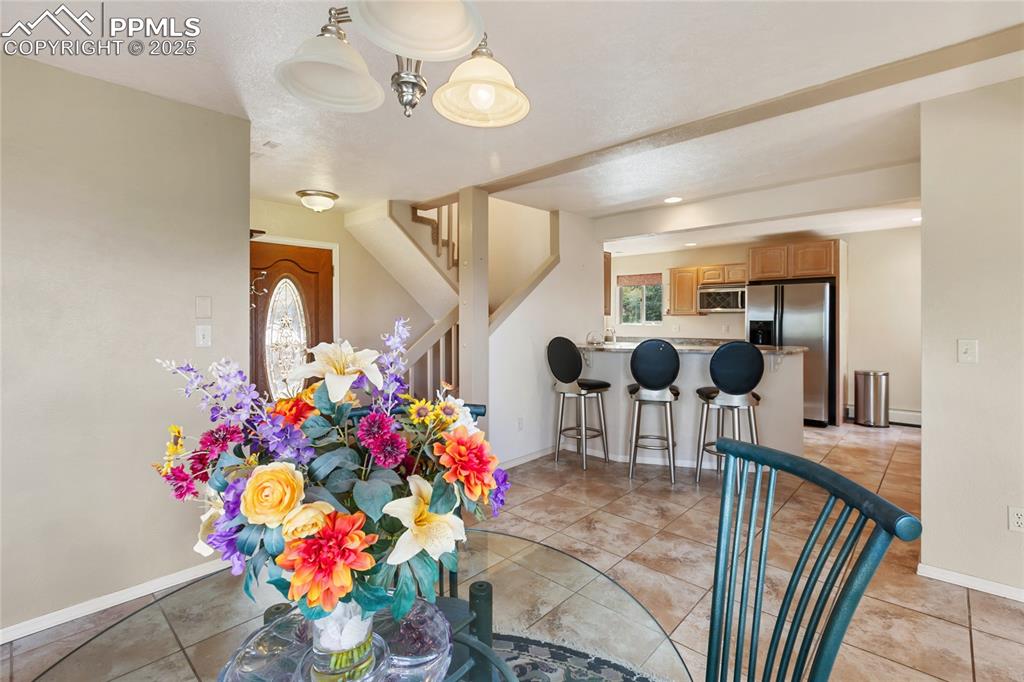 Dining space with light tile patterned floors and stairway