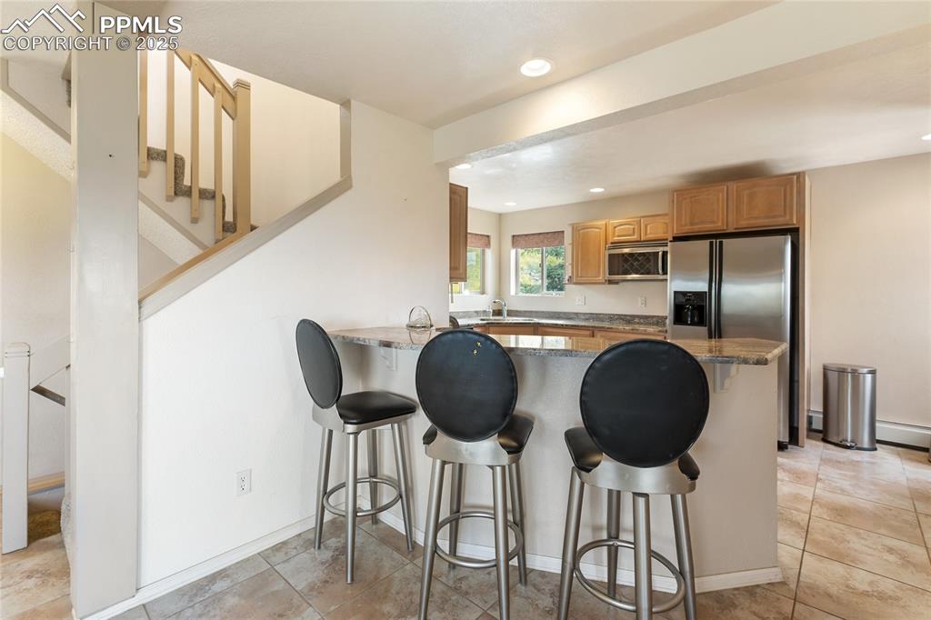 Kitchen featuring a breakfast bar, recessed lighting, a peninsula, appliances with stainless steel finishes, and light tile patterned floors