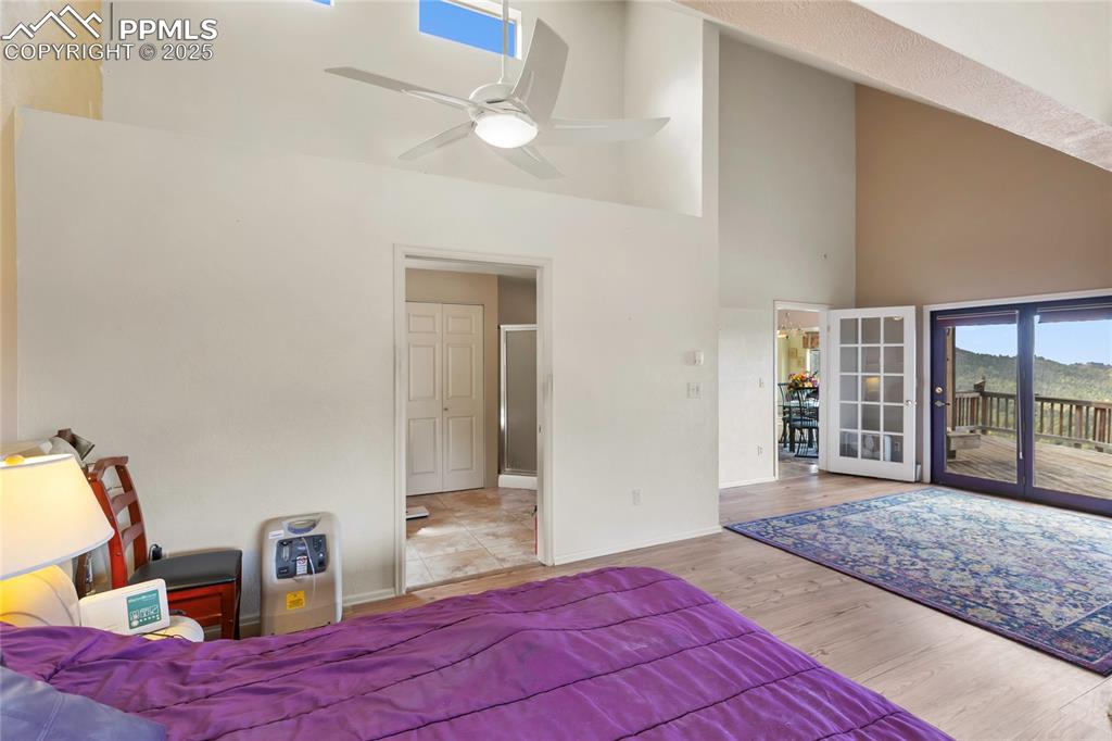 Bedroom with high vaulted ceiling, access to exterior, wood finished floors, and ceiling fan