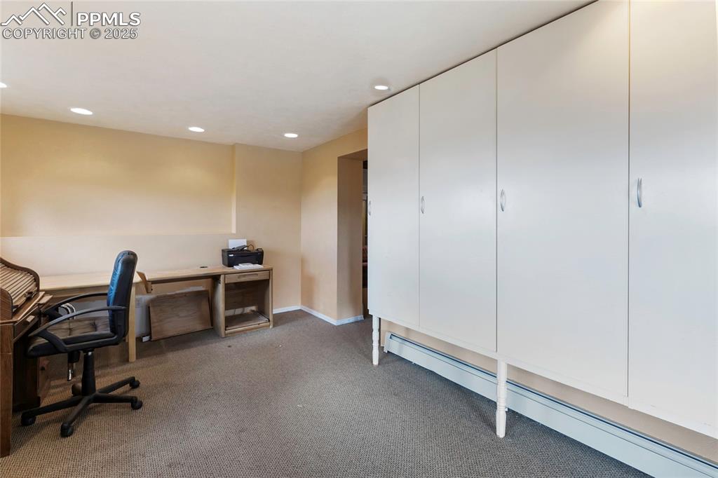Office space with a baseboard radiator, recessed lighting, and light carpet