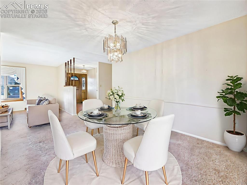 Virtually Staged: Dining Room Toward Foyer (Empty) – View from the dining room toward the formal living area and welcoming entryway with updated flooring (2023) and beveled glass front door.