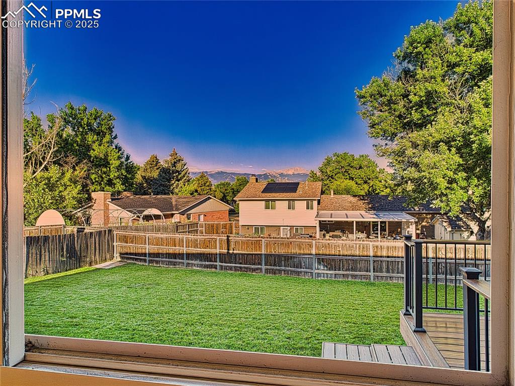 From Dining window Backyard & Deck View – Picture-perfect view of the fenced backyard and Trex deck (2019) with mountain views, offering a peaceful retreat or entertaining space.