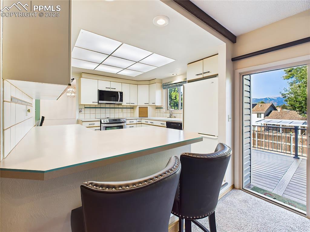 Kitchen Eat-In Bar & Deck Access – Enjoy casual meals or morning coffee at the kitchen bar with stool seating, just steps from the sliding glass door leading to the Trex deck with mountain views.