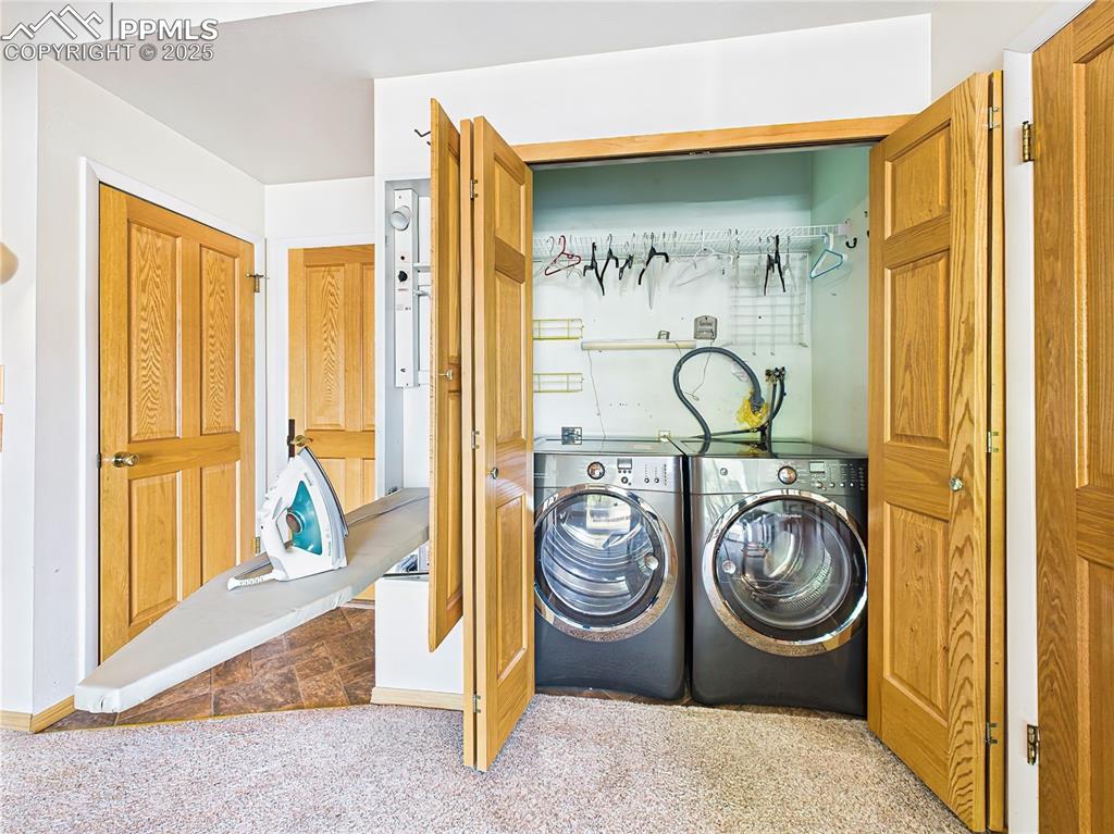 Main Floor Laundry – Convenient main-level laundry closet features a front-loading Maytag washer and dryer, shelving, and a pull-down ironing board for added functionality.