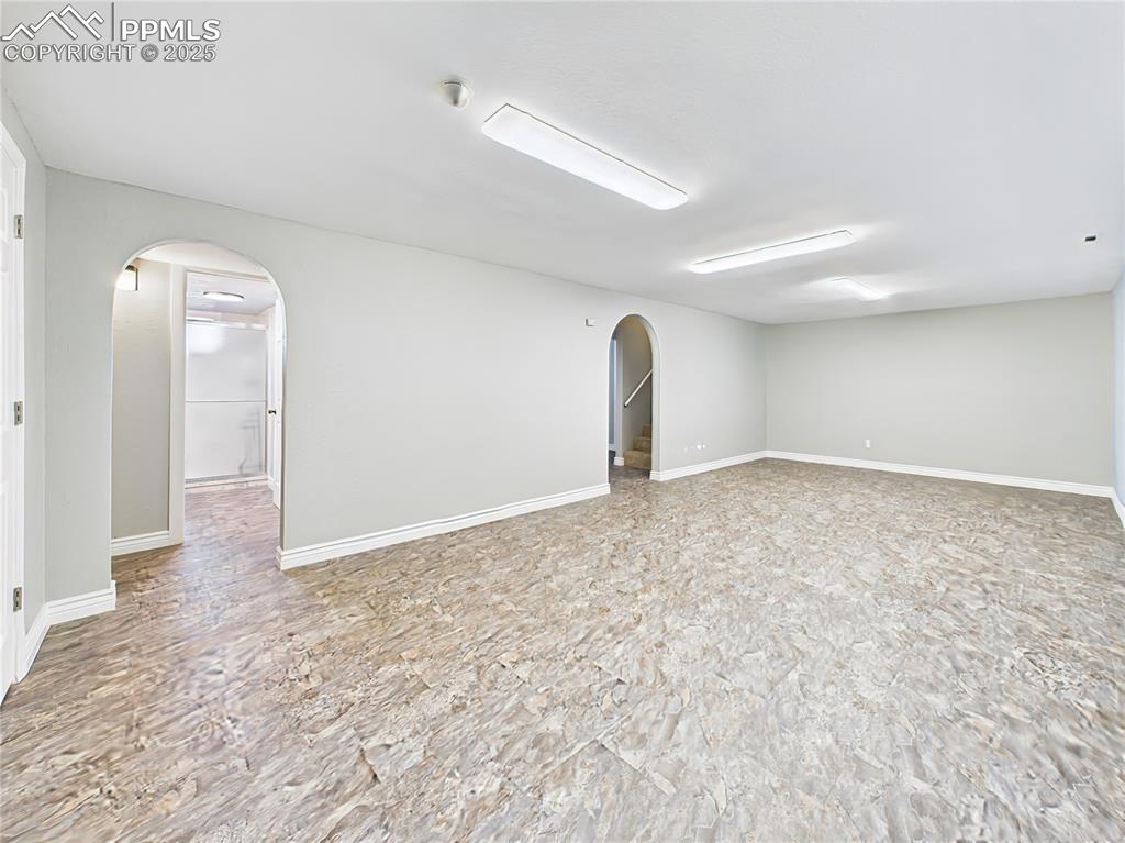 Basement Living Area (Unfurnished) – Open-concept and newly updated with stylish flooring and arched entryways—this space connects seamlessly to other areas of the finished basement.