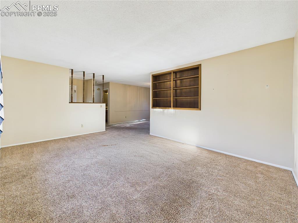 Living Room to Formal Dining View (Empty) – Generously sized living area with built-in wall shelving and a semi-open feel leading to the formal dining space.