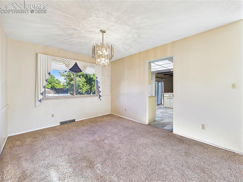 Formal Dining Room (Empty, Kitchen View) – The formal dining room features a large window and chandelier, with direct access to the kitchen for easy entertaining.