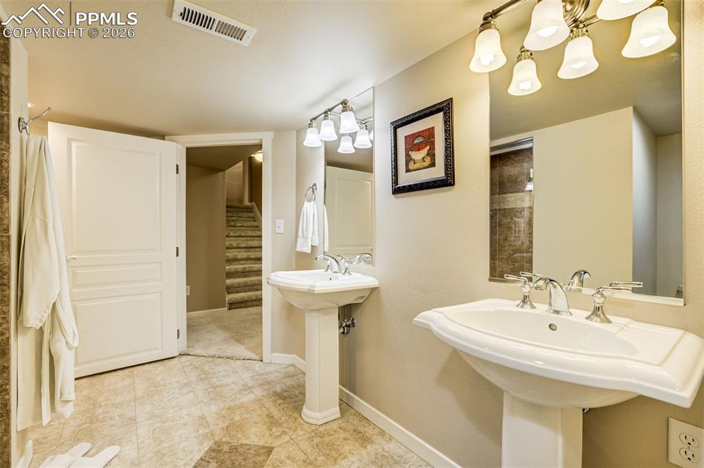 A 3/4 bathroom in basement with two pedestal sinks