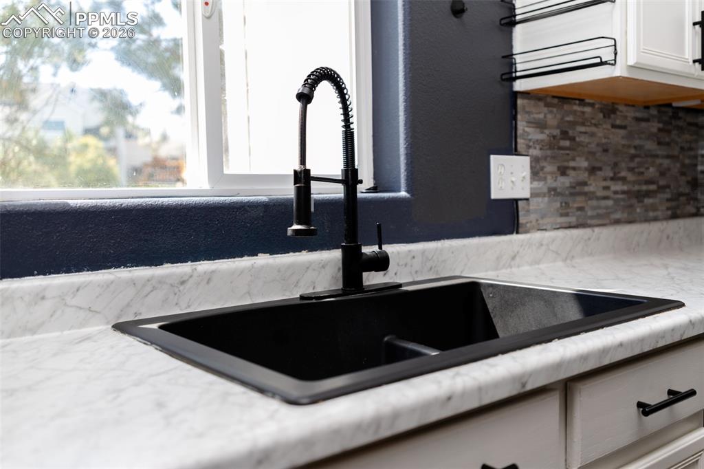 Kitchen view of light stone countertops, backsplash, and white cabinetry