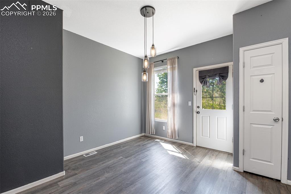Unfurnished dining area with baseboards and wood finished floors