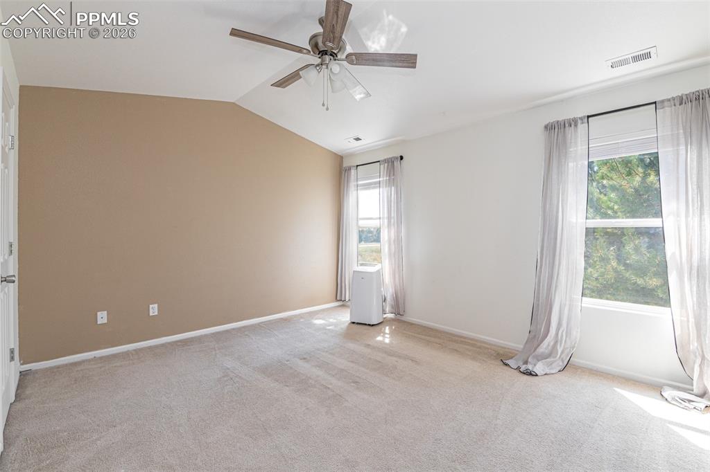 Spare room with ceiling fan, light carpet, and vaulted ceiling