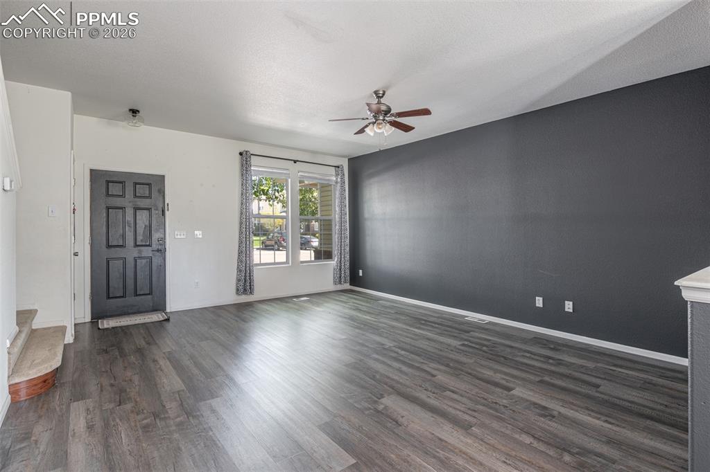 Unfurnished living room featuring dark wood finished floors and a ceiling fan