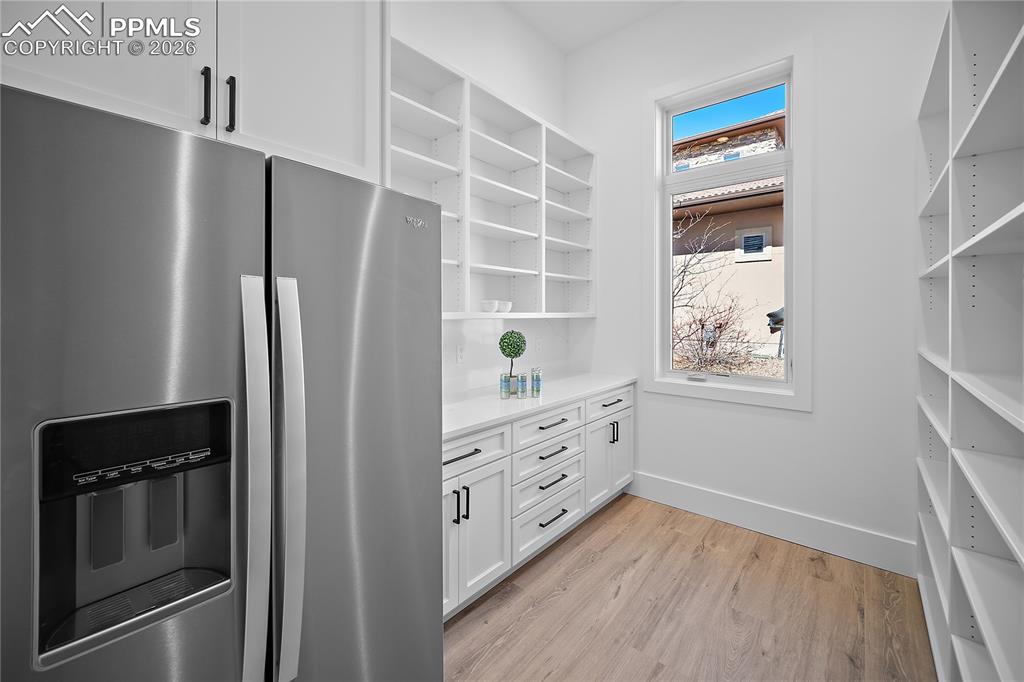 Walk-in pantry with custom cabinetry and fridge
