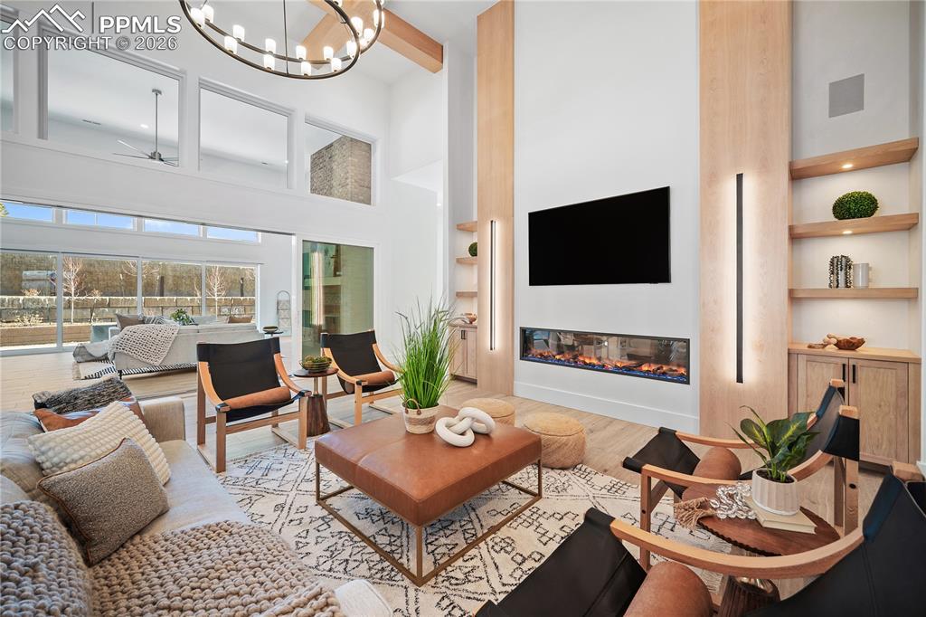 An open floor plan with soaring 18-foot ceilings, highlighted by a striking electric fireplace and comfortable radiant heated floors.