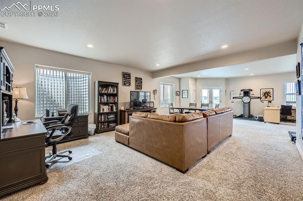 Living area with light colored carpet, an office area, and recessed lighting