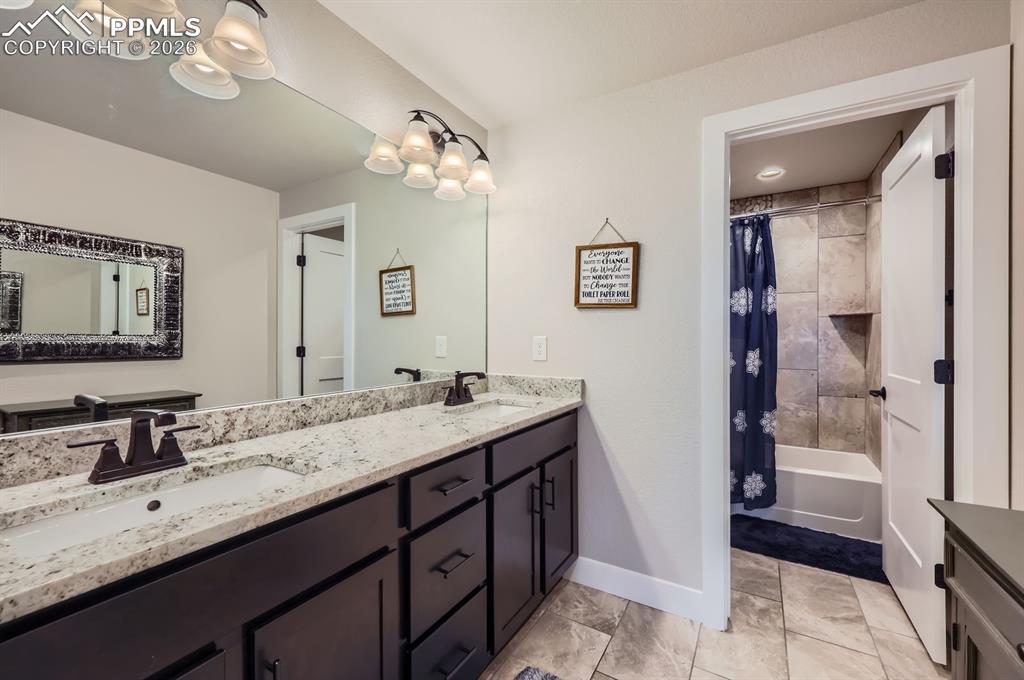 Full bathroom featuring baseboards, double vanity, and shower / tub combo with curtain