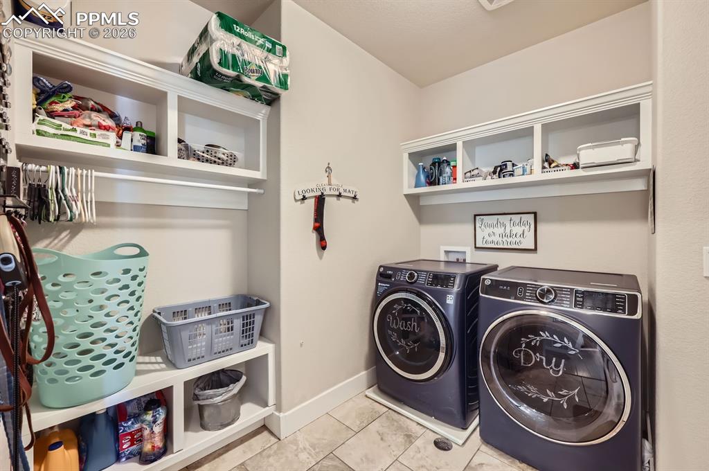 Laundry area featuring washer and clothes dryer, baseboards, and tile patterned flooring