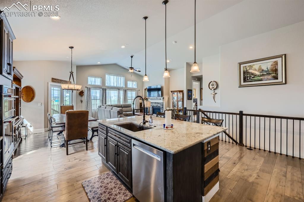 Kitchen with a sink, stainless steel dishwasher, lofted ceiling, ceiling fan, and light wood-type flooring