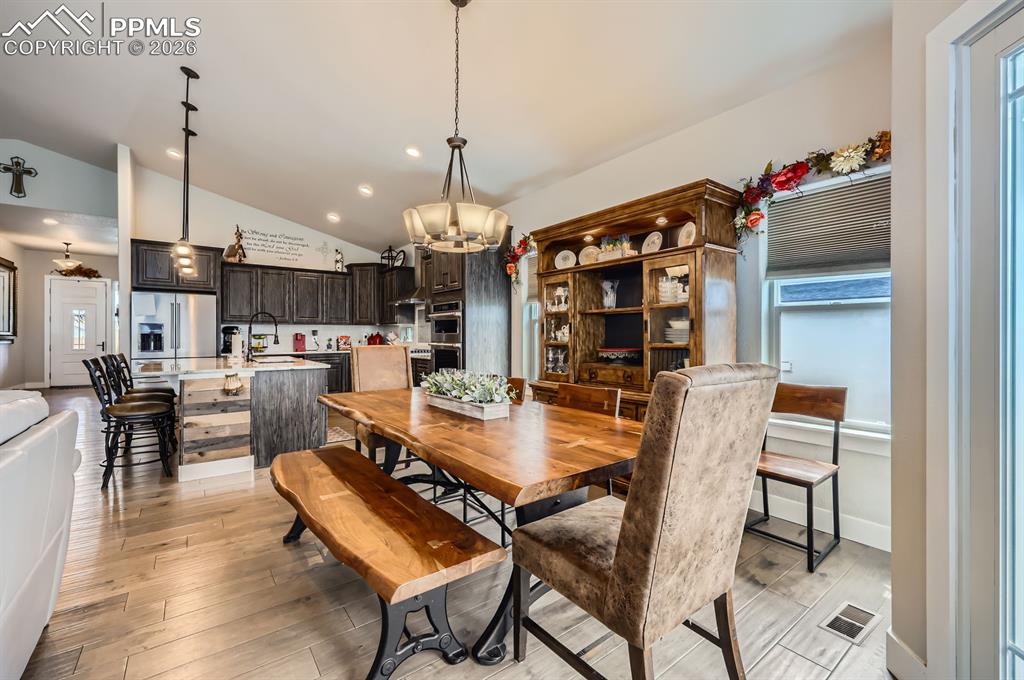 Dining space featuring vaulted ceiling, a chandelier, light wood-type flooring, and recessed lighting
