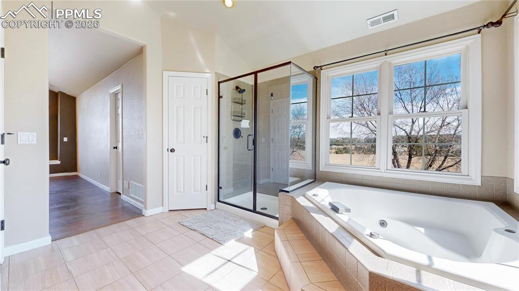 Full bath featuring tiled floors, a whirlpool tub, a shower stall, and lofted ceiling