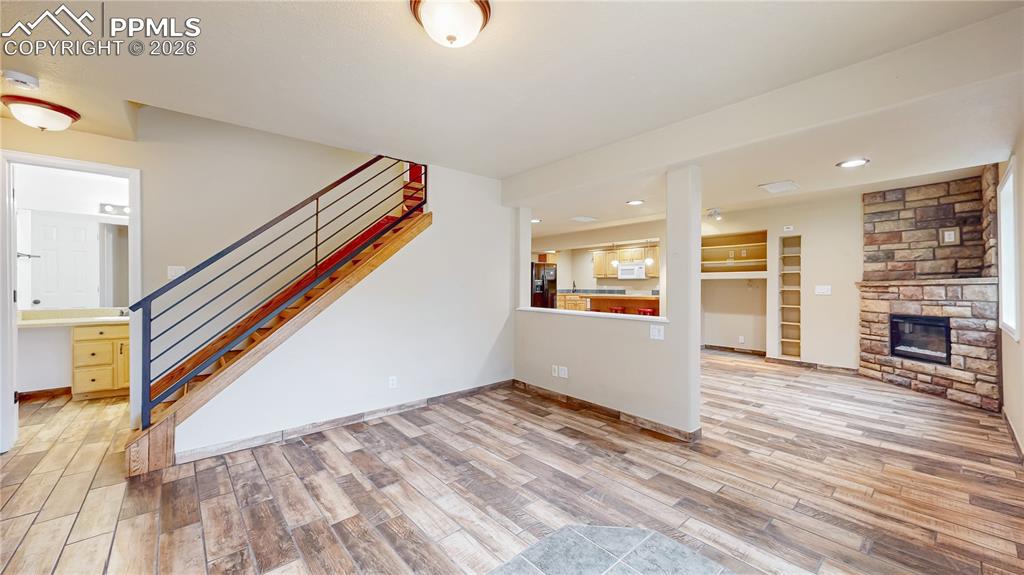 Unfurnished living room with light wood-style floors, a stone fireplace, recessed lighting, and built in shelves