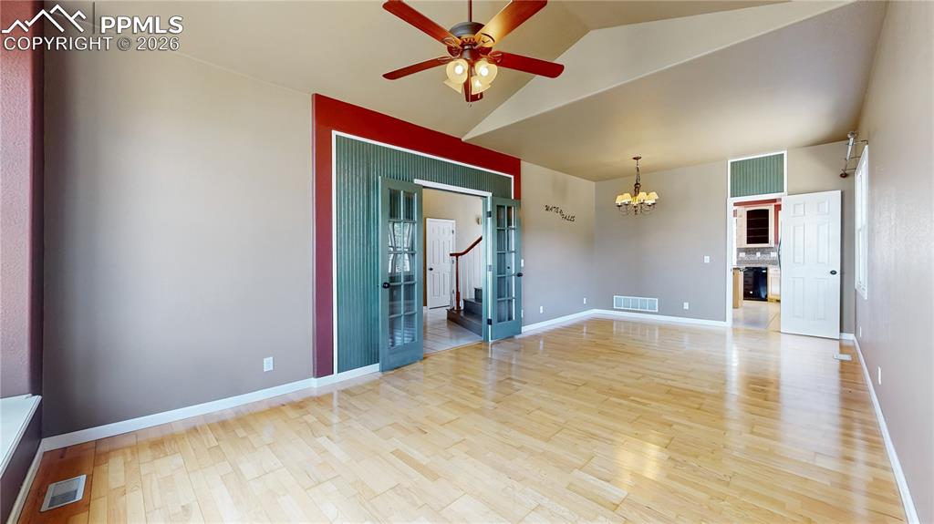 Unfurnished room featuring suspended lighting, ceiling fan, light wood-type flooring, and lofted ceiling