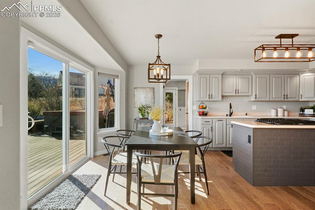 Kitchen with light wood-type flooring, gray cabinetry, decorative light fixtures, and a notable chandelier