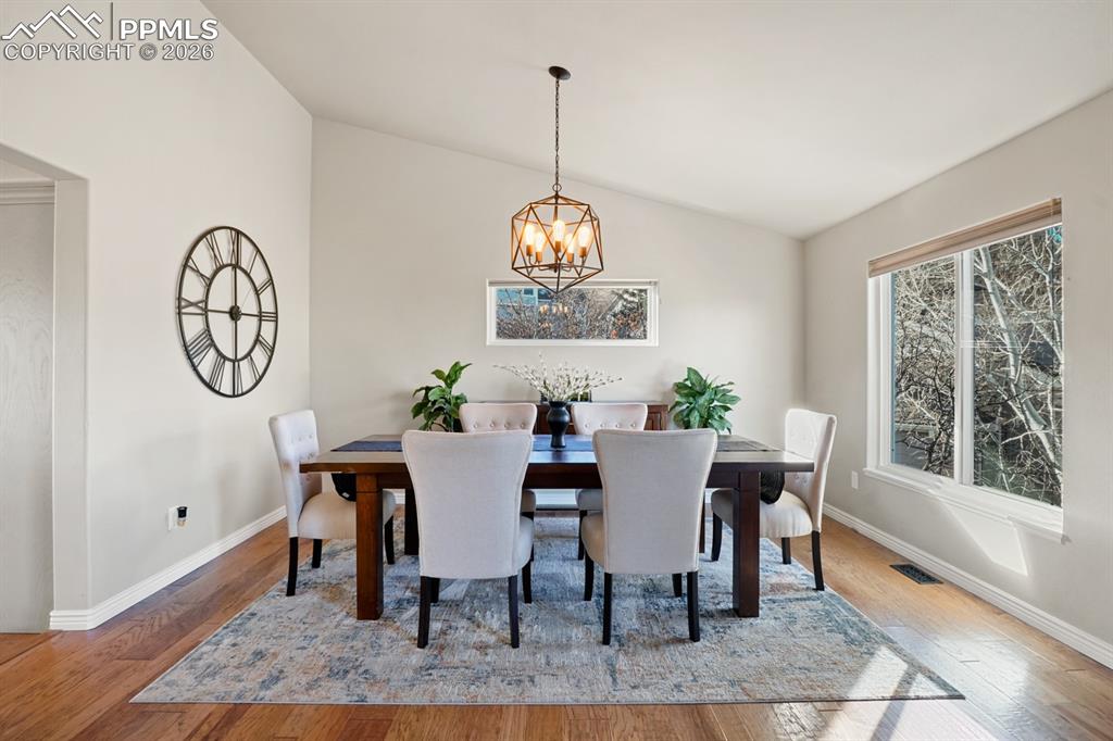 Dining space with lofted ceiling, wood-type flooring, and a chandelier