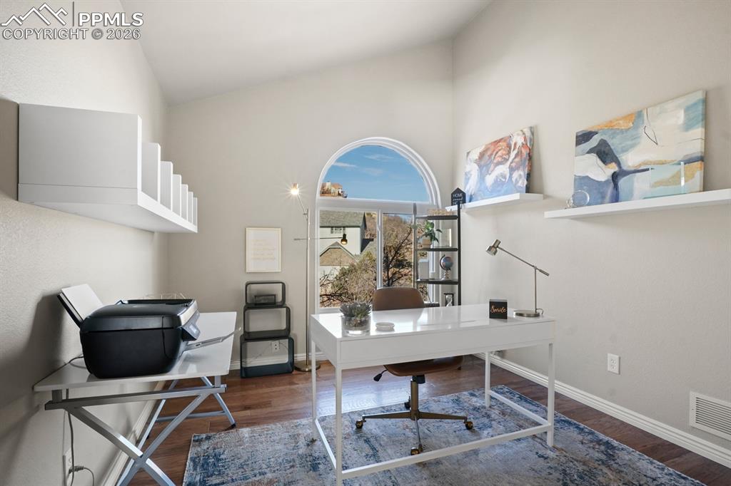 Home office with high vaulted ceiling and dark hardwood / wood-style flooring