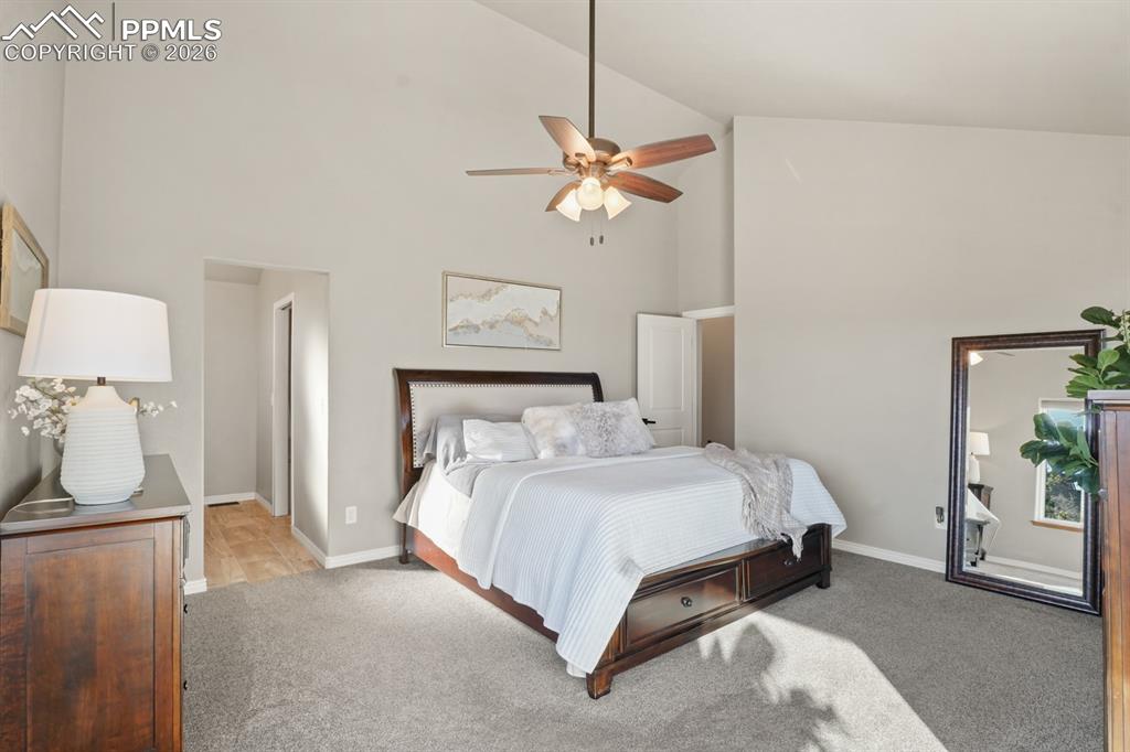Carpeted bedroom featuring high vaulted ceiling and ceiling fan