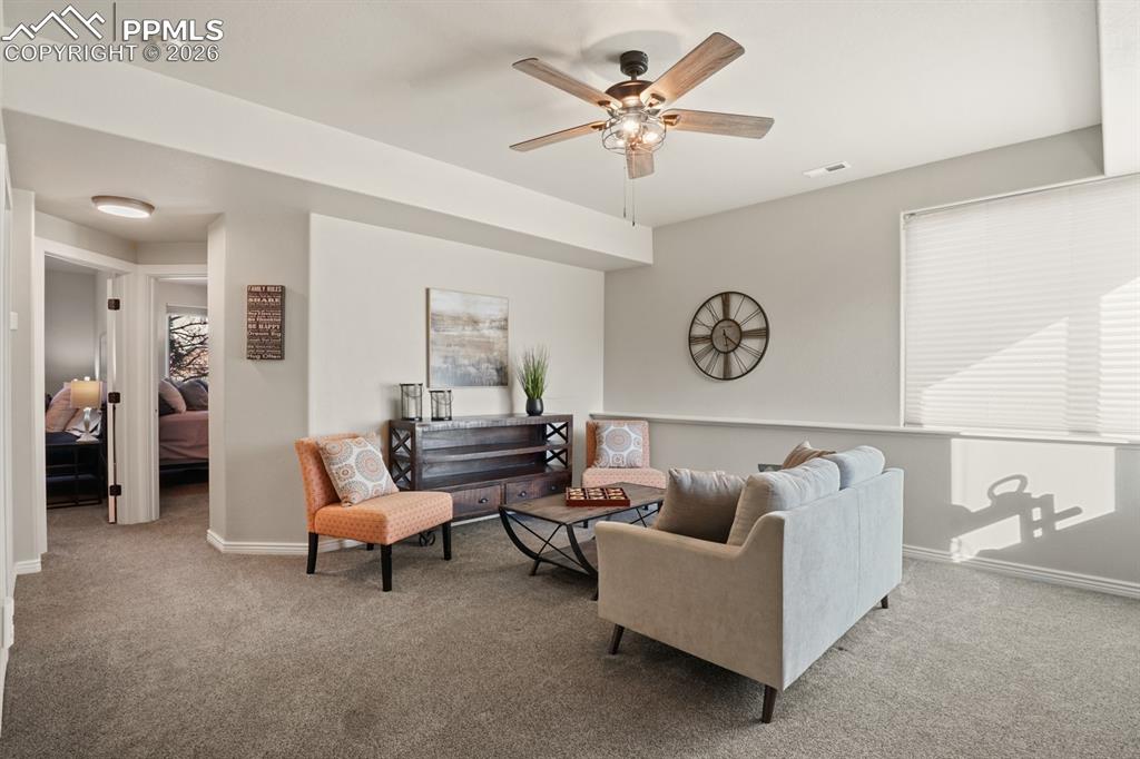 Living room with ceiling fan and light carpet