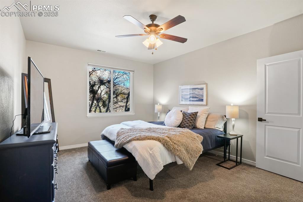 Bedroom featuring ceiling fan and dark colored carpet