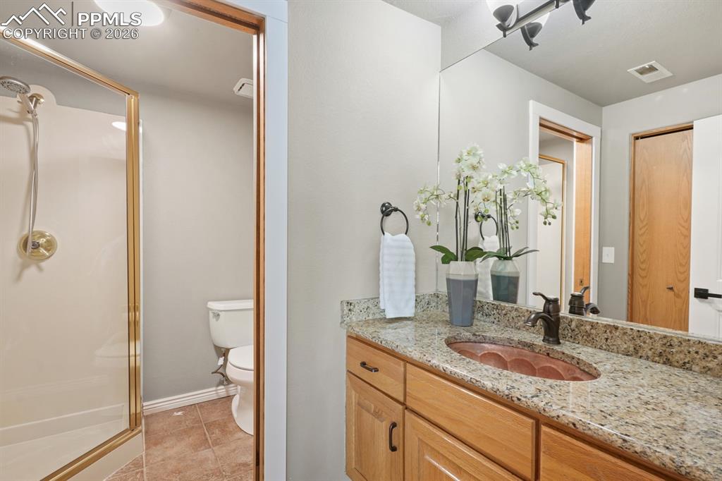 Bathroom with tile patterned flooring, vanity, toilet, and an enclosed shower