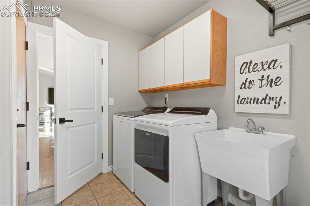 Laundry room with cabinets, separate washer and dryer, light tile patterned floors, and sink