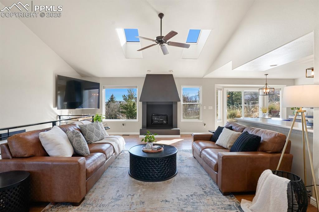 Living room with light wood-type flooring, a skylight, ceiling fan, and a wealth of natural light