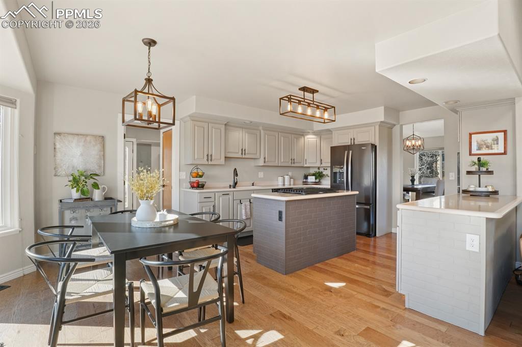 Kitchen with a notable chandelier, light hardwood / wood-style flooring, stainless steel appliances, a kitchen island, and hanging light fixtures