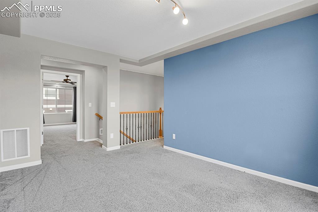 Carpeted empty room with baseboards and a ceiling fan