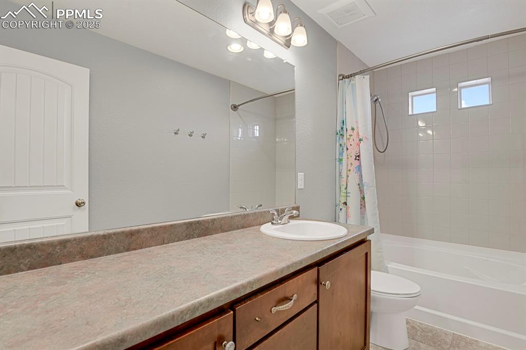 Bathroom featuring vanity, shower / bath combination with curtain, and light tile patterned floors