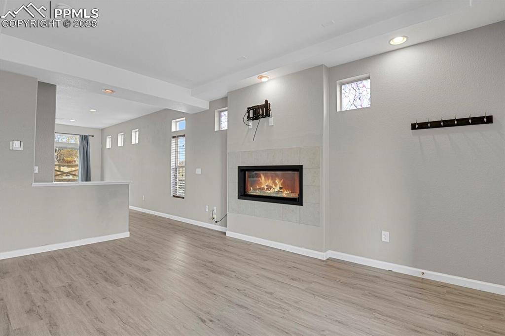Unfurnished living room featuring recessed lighting, a fireplace, healthy amount of natural light, and light wood finished floors