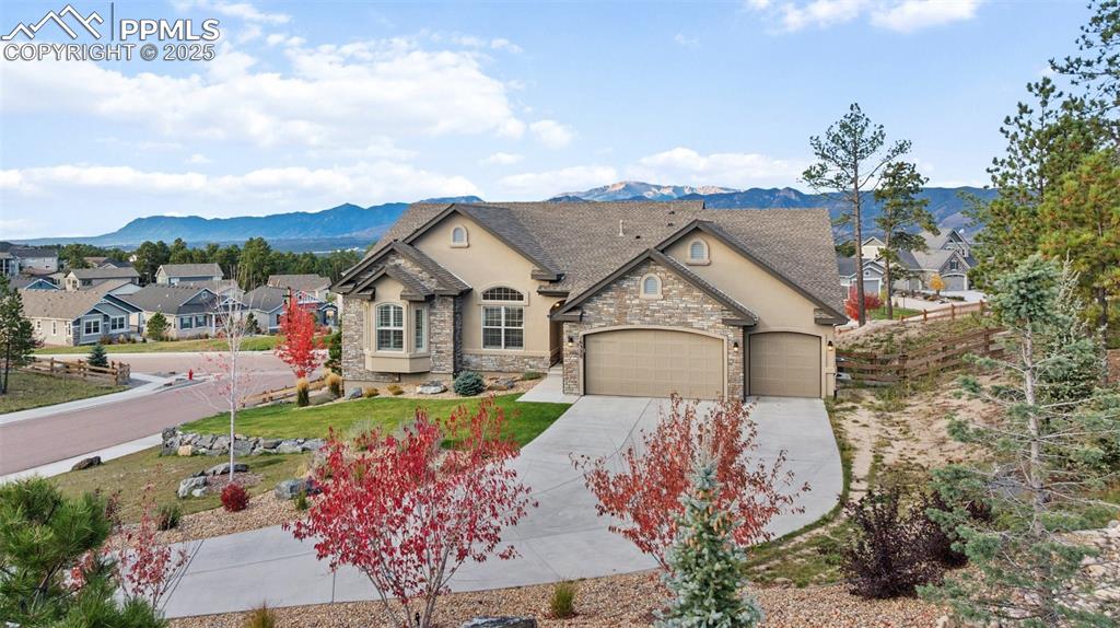 French country style house featuring stucco siding, a mountain view, a front yard, concrete driveway, and a garage
