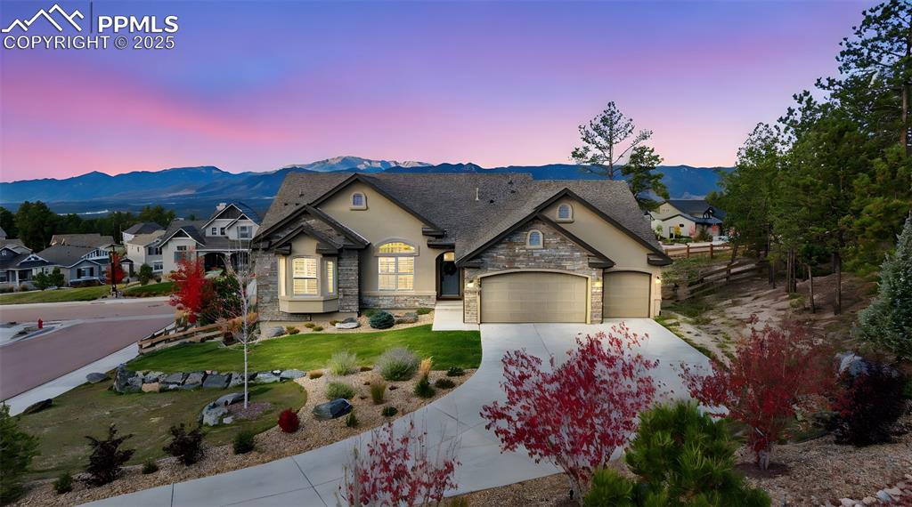 French country style house featuring driveway, stone siding, a mountain view, and stucco siding