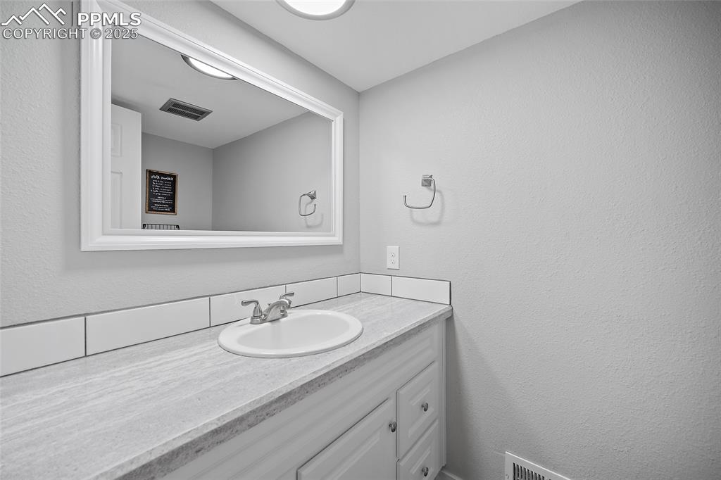 Bathroom with a textured wall and vanity