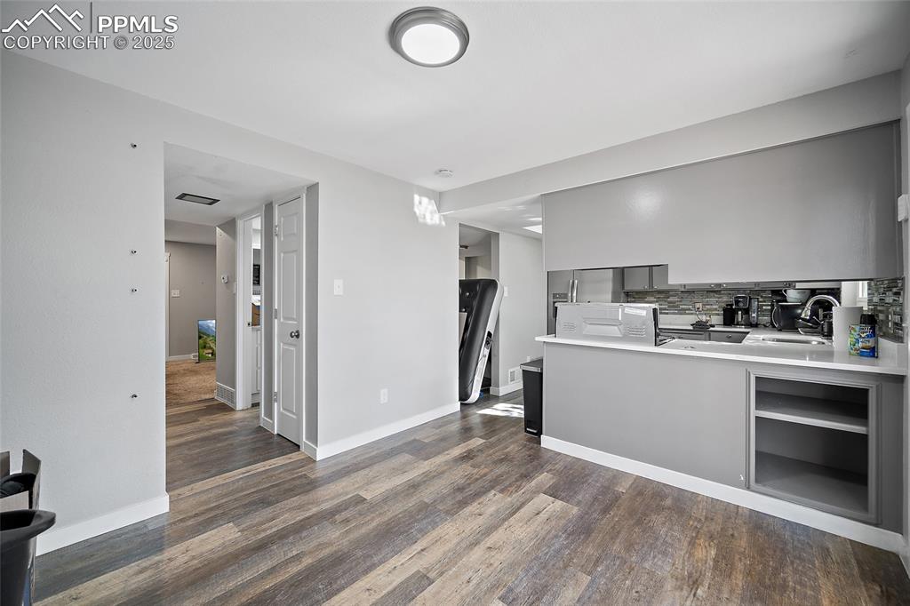 Kitchen with light countertops, stainless steel fridge, a peninsula, dark wood finished floors, and backsplash