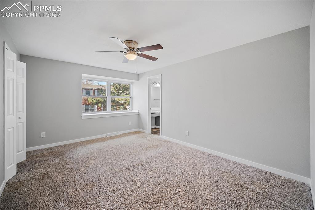 Unfurnished bedroom featuring carpet, a ceiling fan, and ensuite bath