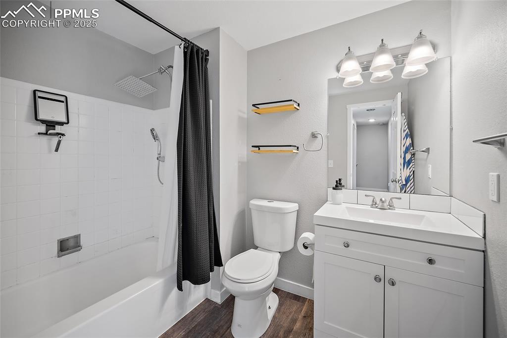 Bathroom featuring shower / bath combo, dark wood-style floors, and vanity