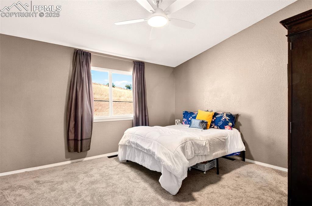 Primary bedroom with a textured wall and ceiling fan